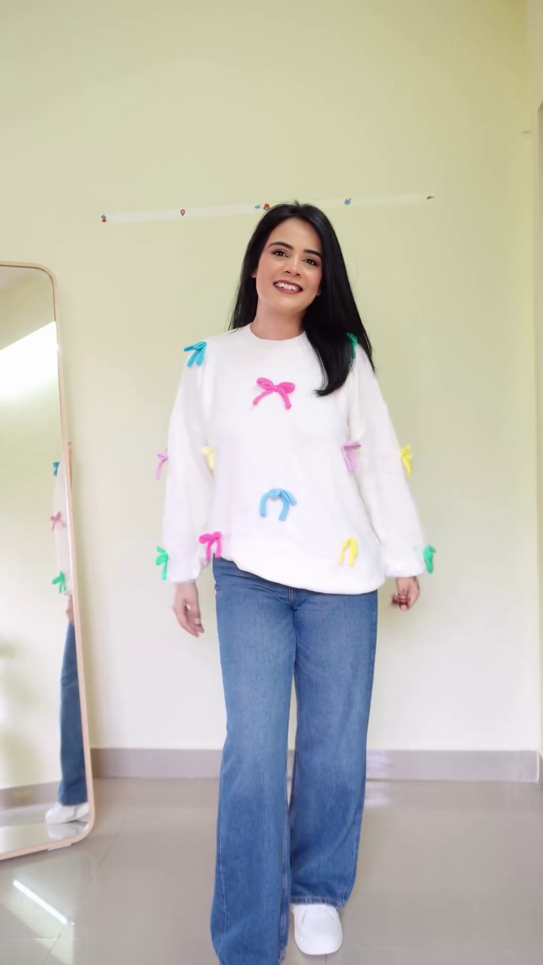 Soft White Fleece Pullover Sweatshirt with Multicolor 3D Bow Appliqué Embellishments and Relaxed Balloon Sleeves Paired with Classic Blue Wide-Leg Denim Jeans